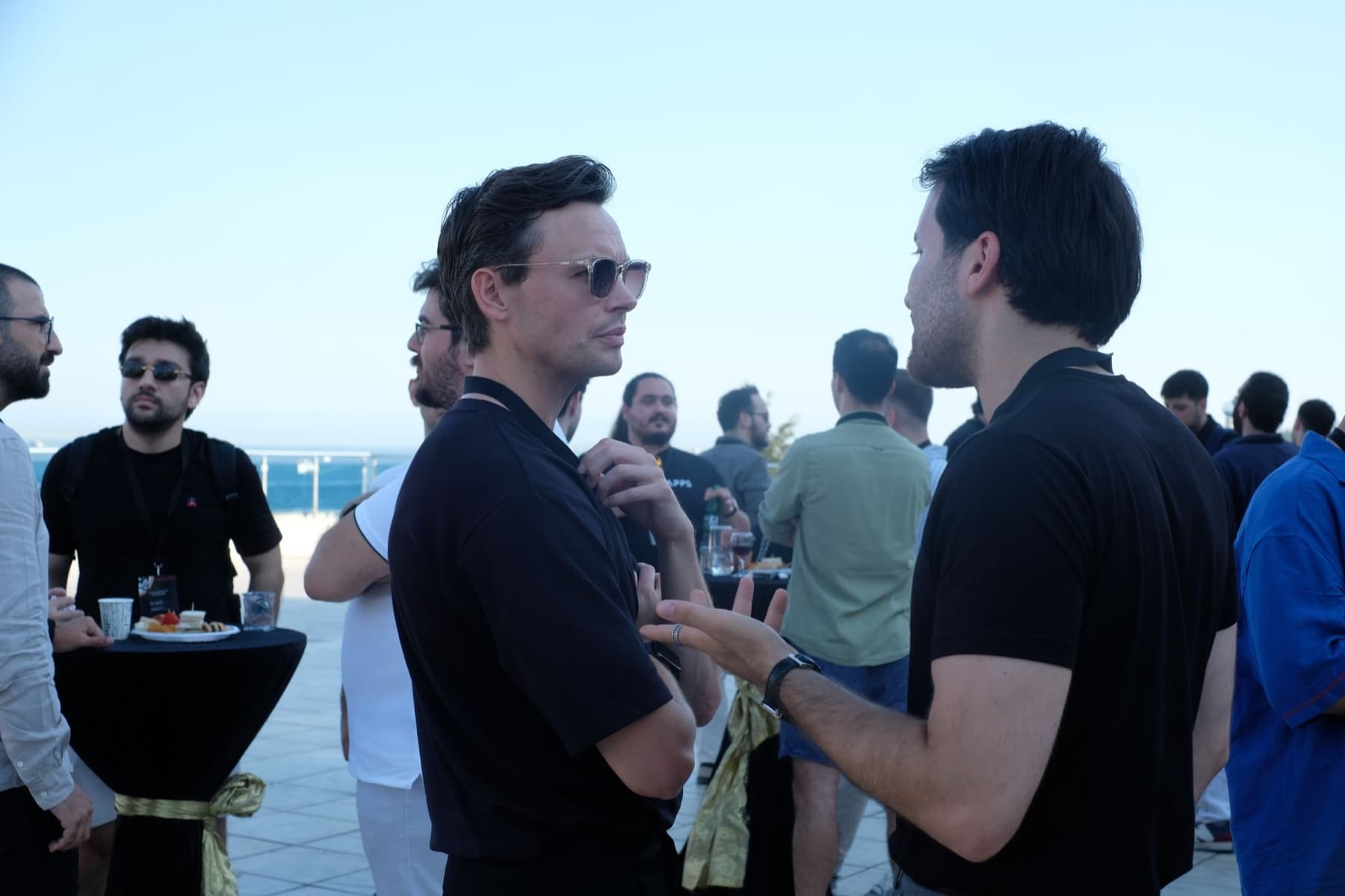 Two founders talking on the terrace at the Neon Apps and RevenueCat App Growth Championship finale in Istanbul with the Bosphorus behind them