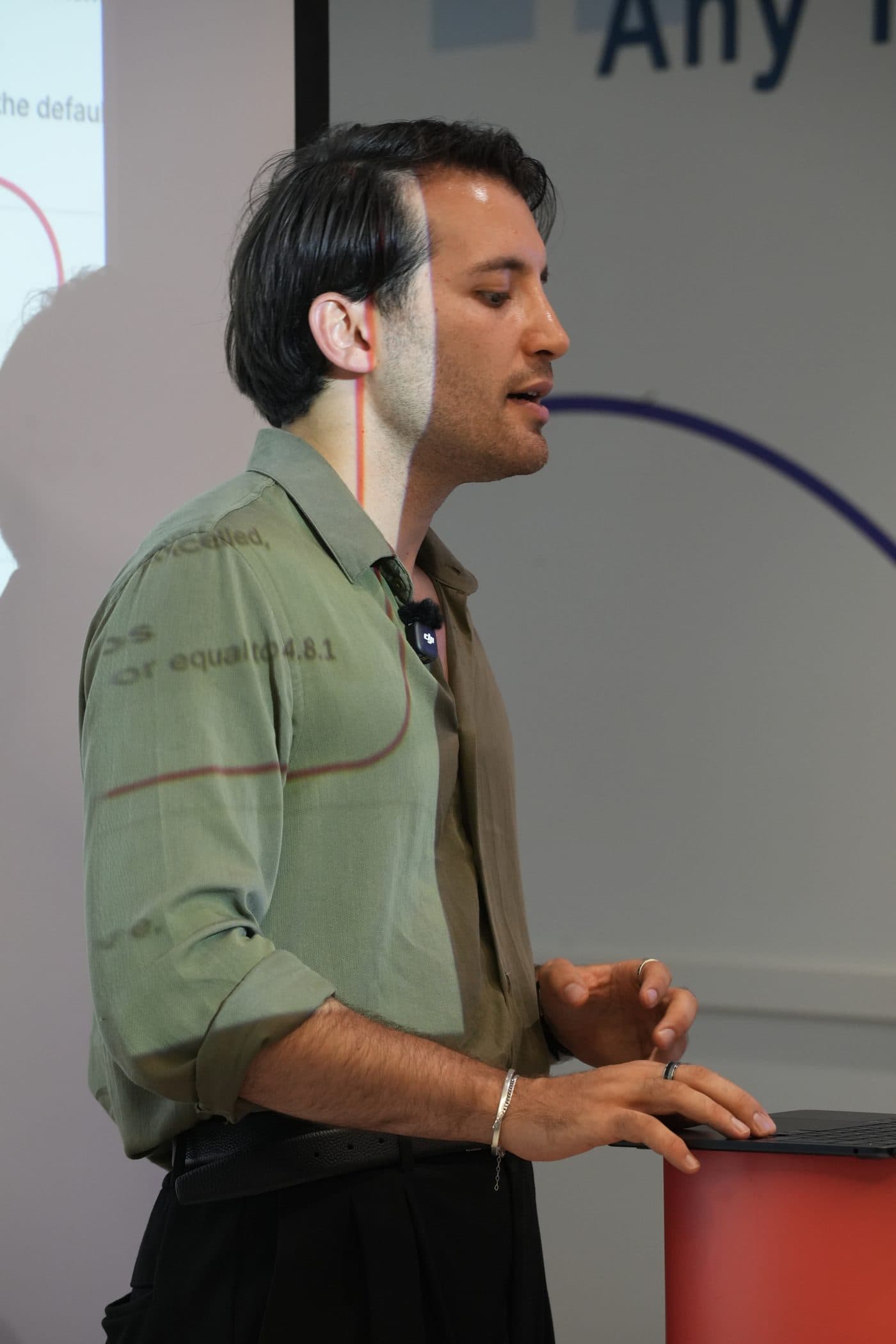 Tyler Blackford speaking, product slides projected on the wall behind him
