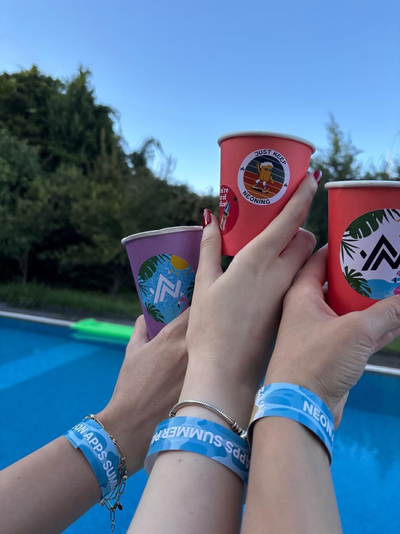 Neon Apps summer party cups and wristbands raised by the pool