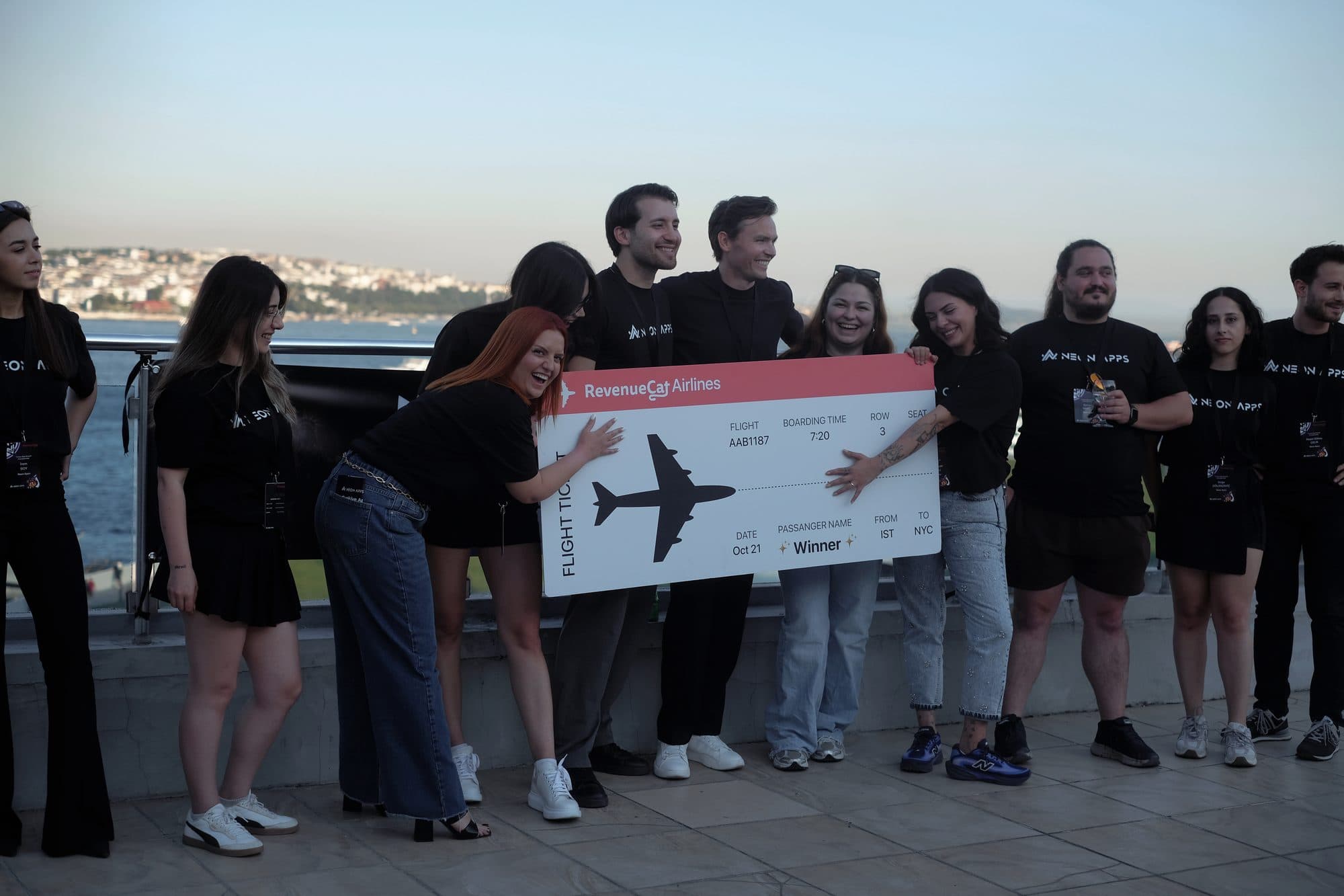 The Neon Apps team on the Bosphorus terrace at the App Growth Championship finale in Istanbul holding the oversized New York flight ticket, July 2026