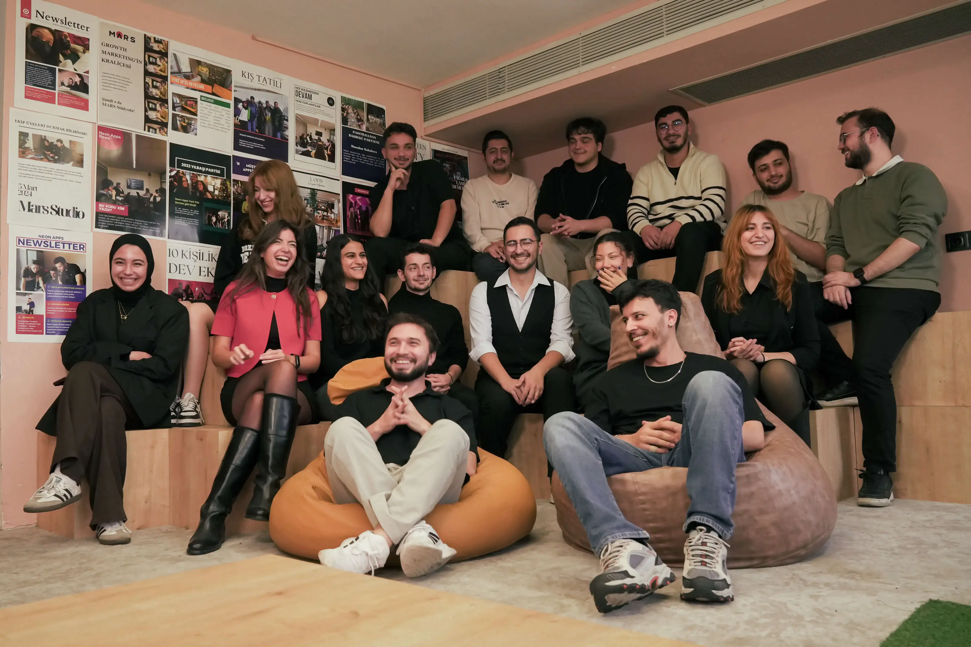 Part of the Neon Apps team in the Istanbul office, in front of a wall of the company's own newsletters